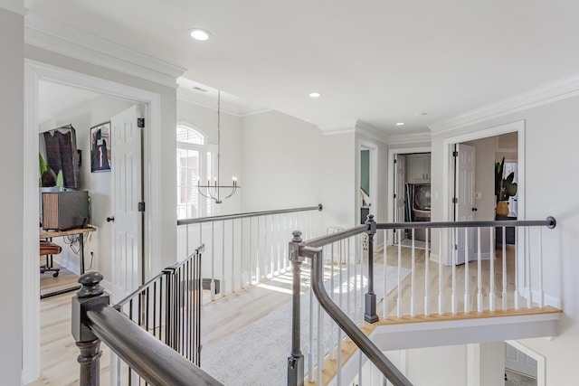 corridor with an inviting chandelier, crown molding, and light hardwood / wood-style flooring