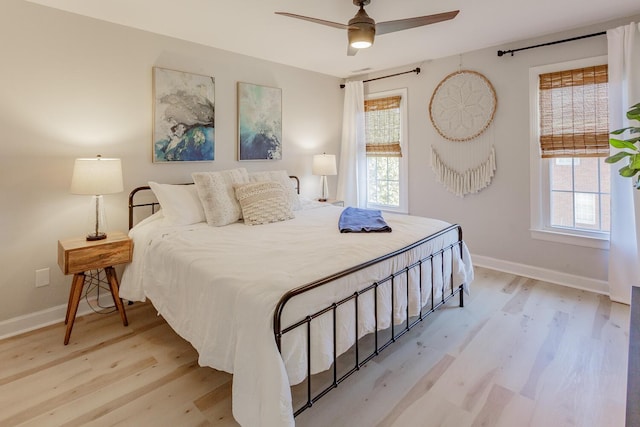 bedroom with ceiling fan, multiple windows, and light wood-type flooring