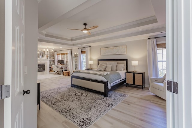 bedroom with a raised ceiling, ornamental molding, and light hardwood / wood-style floors