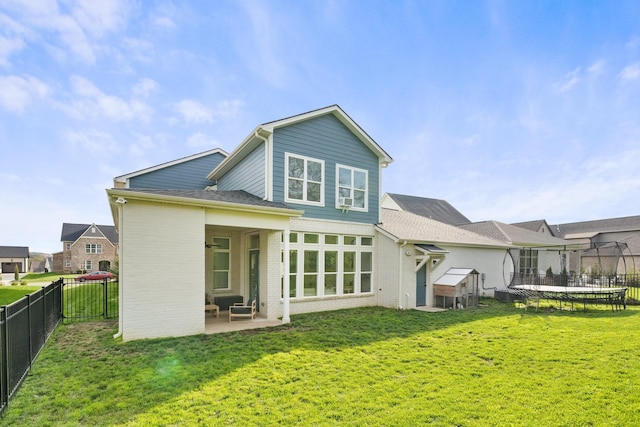 rear view of property with a patio area, a trampoline, and a lawn