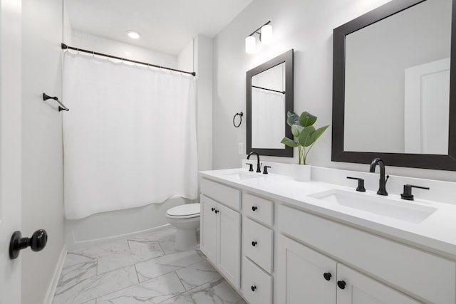 bathroom featuring double vanity, marble finish floor, toilet, and a sink