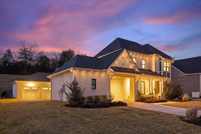 view of front of property with a garage, brick siding, a lawn, and an outdoor structure