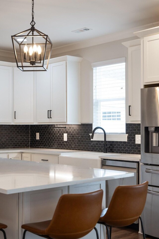 kitchen featuring appliances with stainless steel finishes, a breakfast bar area, visible vents, and tasteful backsplash