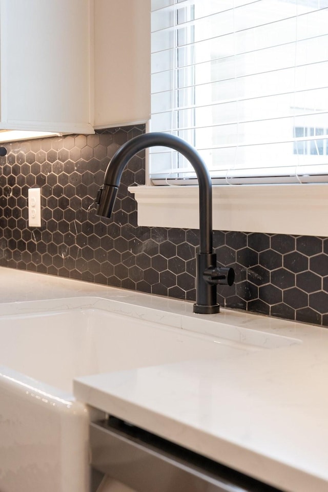 details featuring tasteful backsplash, light countertops, and a sink