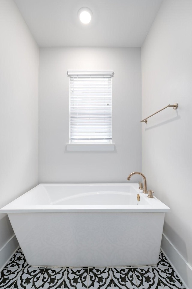 bathroom featuring a soaking tub and baseboards