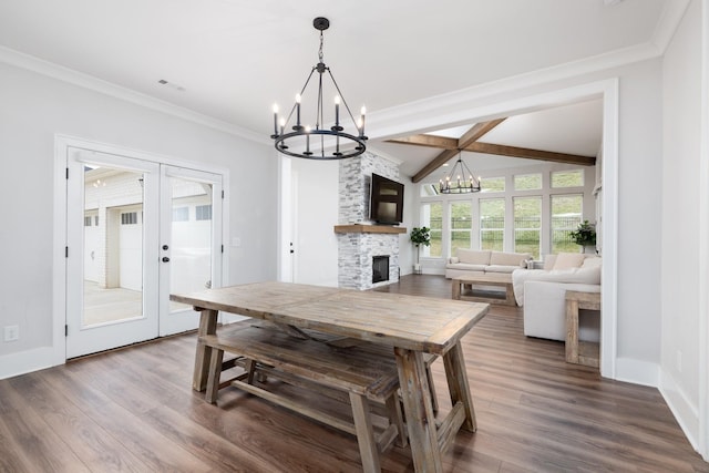 dining room with french doors, a fireplace, wood finished floors, and an inviting chandelier