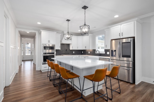 kitchen featuring a breakfast bar area, dark wood-style flooring, a kitchen island, white cabinets, and appliances with stainless steel finishes