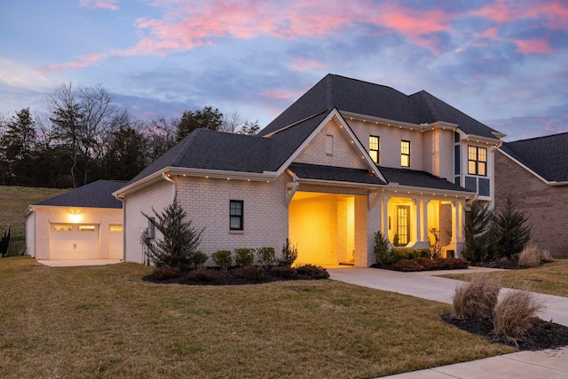 view of front of house featuring an outbuilding, driveway, a yard, and brick siding