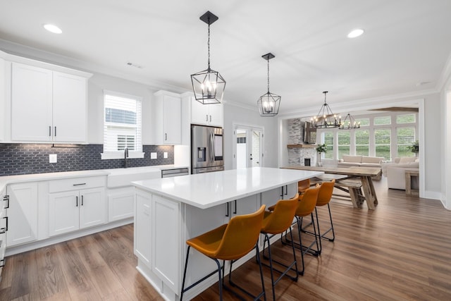 kitchen with ornamental molding, a center island, a sink, and stainless steel fridge with ice dispenser