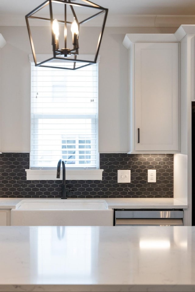 kitchen featuring white cabinets, ornamental molding, a sink, light countertops, and backsplash