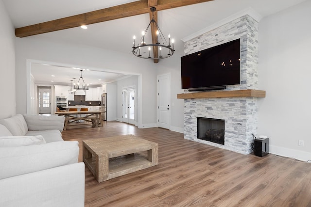 living room with a fireplace, an inviting chandelier, light wood-type flooring, beamed ceiling, and baseboards