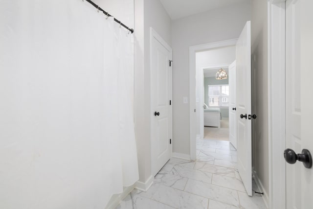 corridor featuring marble finish floor and baseboards