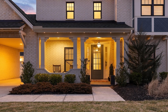 entrance to property with a porch and brick siding