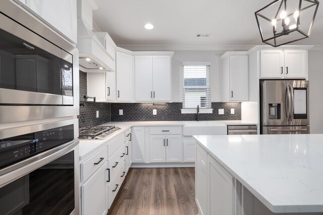 kitchen featuring stainless steel appliances, tasteful backsplash, a sink, and custom range hood