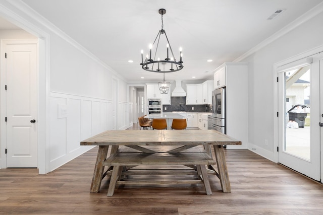 dining area featuring french doors, visible vents, an inviting chandelier, ornamental molding, and wood finished floors