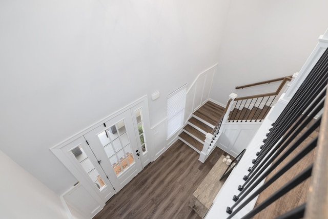 stairway with a high ceiling, baseboards, and wood finished floors