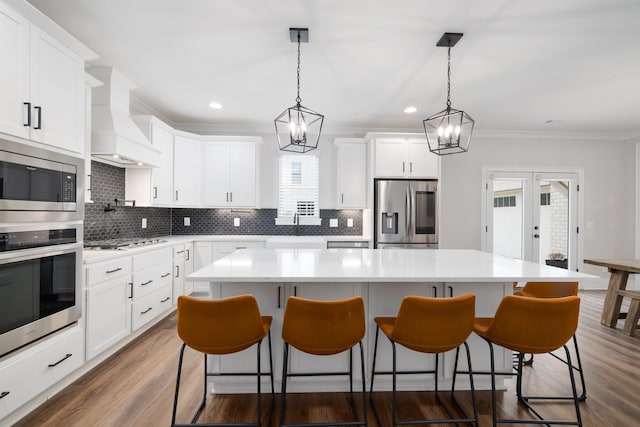 kitchen featuring stainless steel appliances, backsplash, custom exhaust hood, a center island, and dark wood finished floors