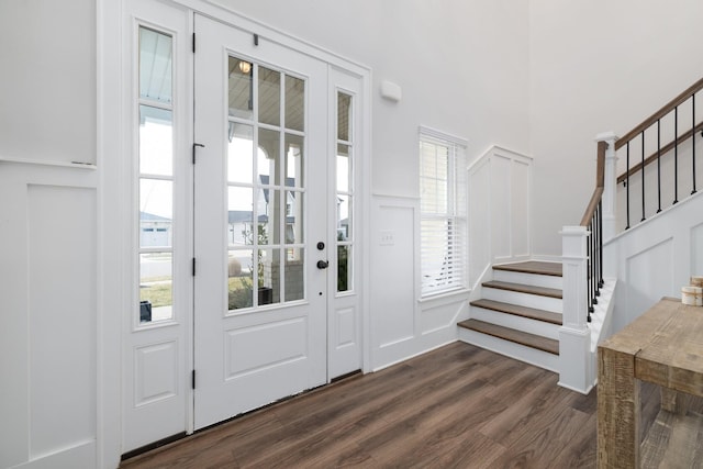 foyer with a wainscoted wall, stairway, a decorative wall, and dark wood-type flooring