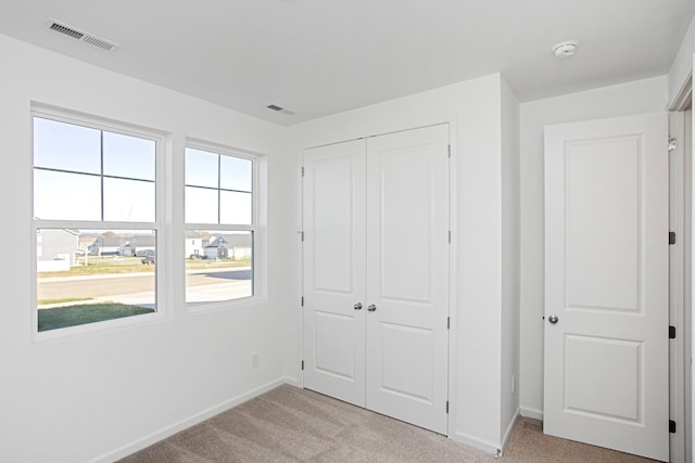 unfurnished bedroom featuring light colored carpet and a closet