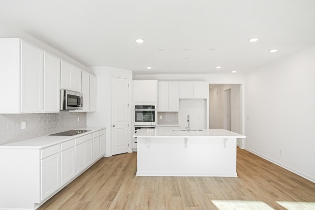 kitchen featuring white cabinetry, sink, light hardwood / wood-style floors, stainless steel appliances, and a center island with sink