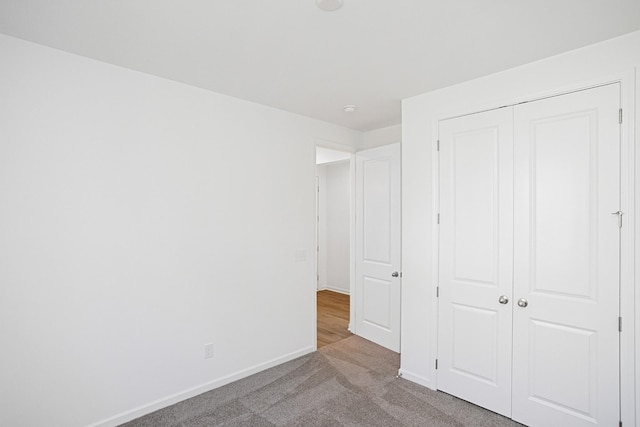 unfurnished bedroom with light colored carpet and a closet