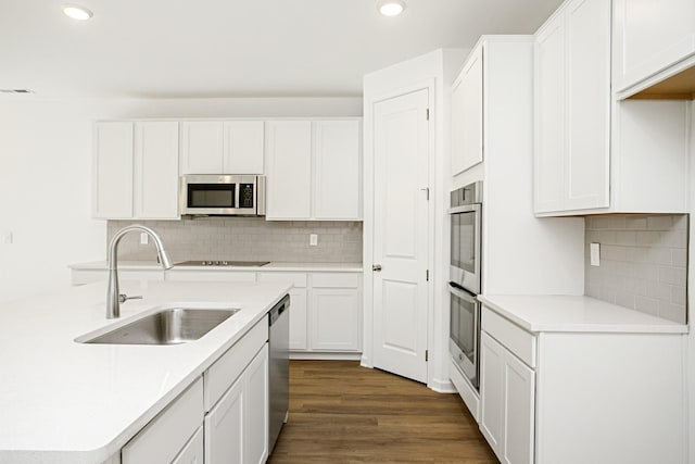 kitchen featuring sink, white cabinets, backsplash, stainless steel appliances, and dark wood-type flooring