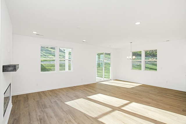 unfurnished living room with a notable chandelier and light hardwood / wood-style flooring