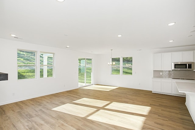 unfurnished living room featuring an inviting chandelier and light wood-type flooring