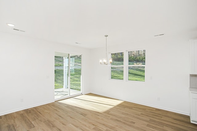 unfurnished room featuring wood-type flooring and an inviting chandelier