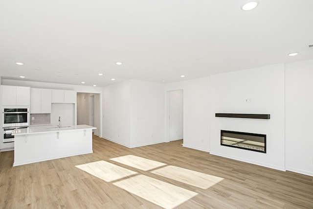 unfurnished living room with sink and light wood-type flooring