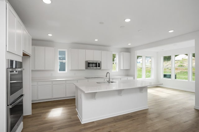 kitchen featuring sink, white cabinetry, a center island with sink, appliances with stainless steel finishes, and dark hardwood / wood-style flooring