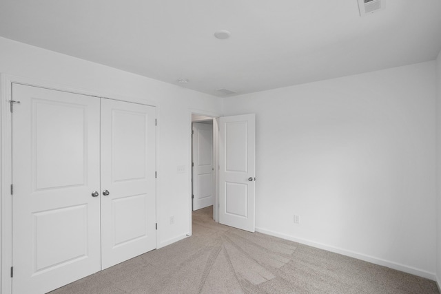 unfurnished bedroom with a closet and light carpet