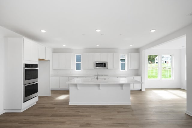 kitchen featuring stainless steel appliances, white cabinetry, a kitchen island with sink, and sink