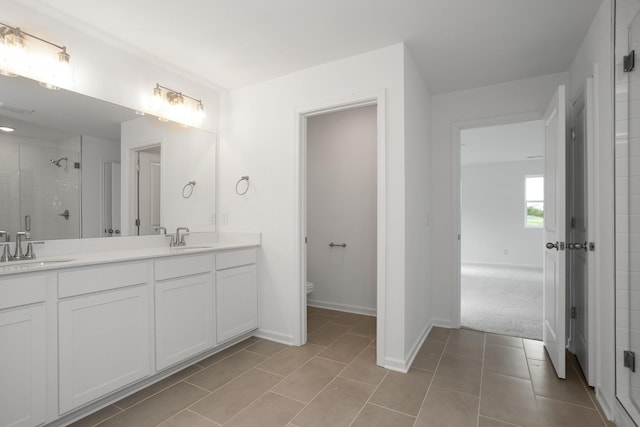 bathroom featuring tile patterned flooring, vanity, a shower with shower door, and toilet