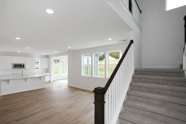 stairway featuring wood-type flooring and sink