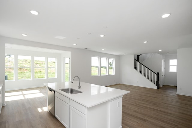 kitchen with sink, white cabinetry, light hardwood / wood-style floors, a center island with sink, and stainless steel dishwasher