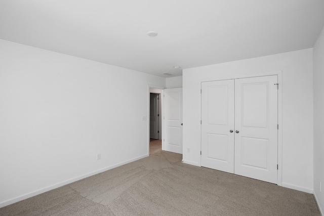 unfurnished bedroom with light colored carpet and a closet