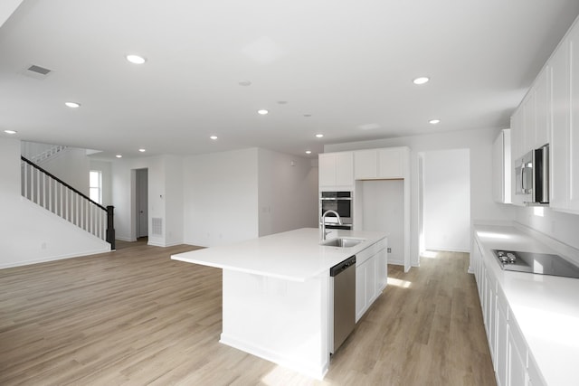 kitchen featuring white cabinetry, appliances with stainless steel finishes, sink, and a center island with sink