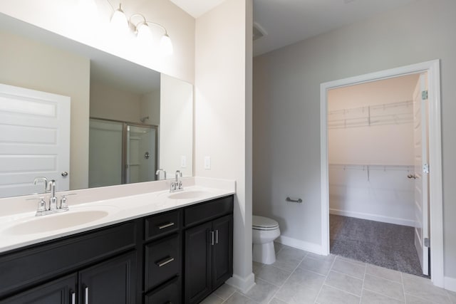 bathroom with a shower with door, vanity, tile patterned flooring, and toilet