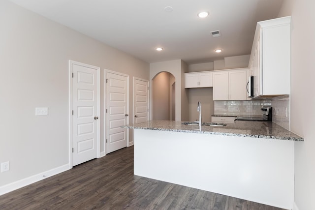 kitchen featuring sink, kitchen peninsula, stove, light stone countertops, and white cabinets