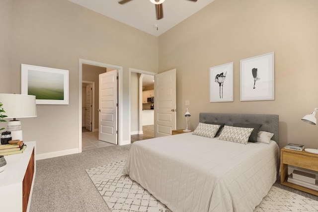 bedroom with a high ceiling, light colored carpet, and ceiling fan