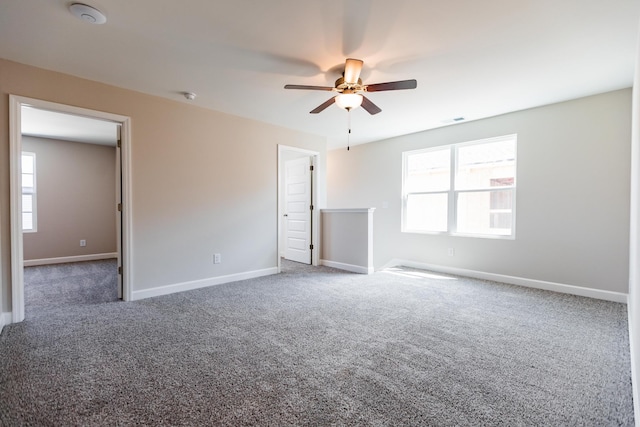 empty room with ceiling fan and dark colored carpet