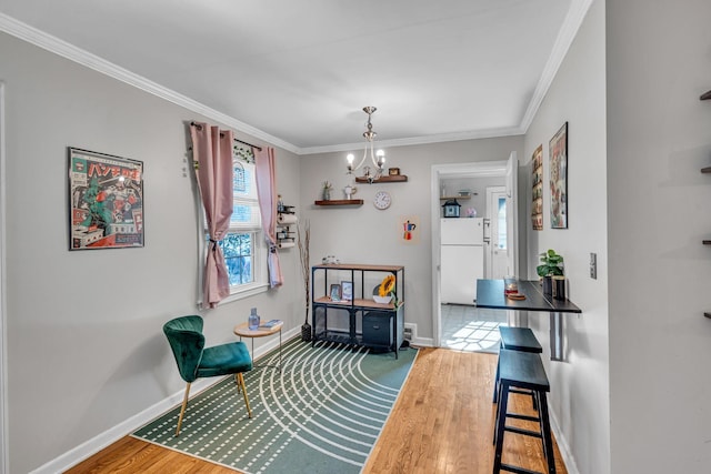 sitting room with an inviting chandelier, hardwood / wood-style flooring, and ornamental molding