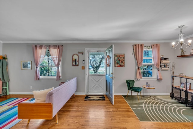 entrance foyer with a wealth of natural light, ornamental molding, hardwood / wood-style floors, and a notable chandelier