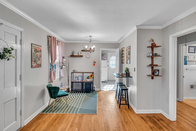 dining area with crown molding, an inviting chandelier, and light wood-type flooring