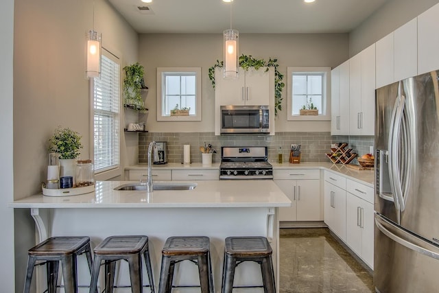 kitchen featuring white cabinetry, sink, decorative light fixtures, and appliances with stainless steel finishes