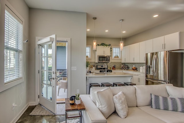 kitchen featuring sink, stainless steel appliances, decorative backsplash, white cabinets, and decorative light fixtures