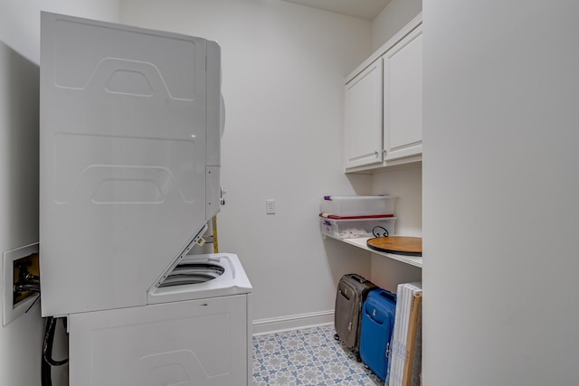 clothes washing area with cabinets and stacked washer / drying machine