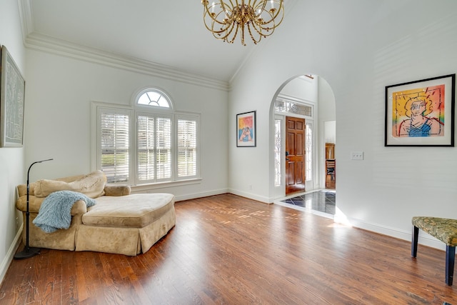 living area with high vaulted ceiling, ornamental molding, a chandelier, and hardwood / wood-style floors