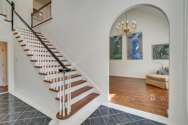 staircase with a high ceiling, ornamental molding, tile patterned floors, and an inviting chandelier